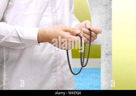Muslim man praying with prayer beads on his hands inside the mosque Stock Photo