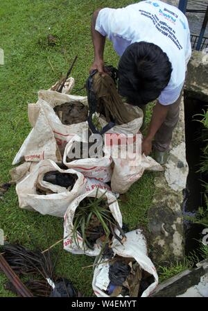 Bogor, West Java, Indonesia - July 2019 : A man put neighborhood trash in a plastic sack. Stock Photo