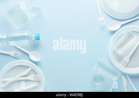 White plastic disposable tableware and containers on blue background. Frame backdrop with copy space. Stock Photo