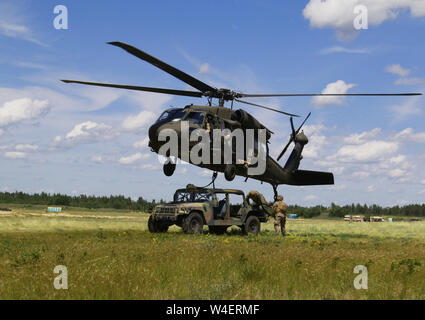 Members of Alpha Company, 1st of the 158th Assault Helicopter Battalion operate a UH-60 to perform sling load operations during Northern Strike 19 on Camp Grayling, Michigan, July 21, 2019. Northern Strike 19 is a National Guard Bureau-sponsored exercise uniting service member from more than 20 states, multiple service branches and numerous coalition countries during the last two weeks of July 2019 at the Camp Grayling Joint Maneuver Training Center and the Alpena Combat Readiness Training Center. (U.S. Army National Guard photo by Army Sgt. Priscilla Desormeaux/Released) (Photograph cropped t Stock Photo