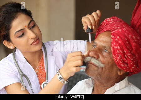 Female doctor putting eye drops in a old man eye Stock Photo