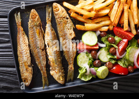 Fried boops boops fish with fresh vegetable salad and french fries close-up on a plate on the table. horizontal top view from above Stock Photo