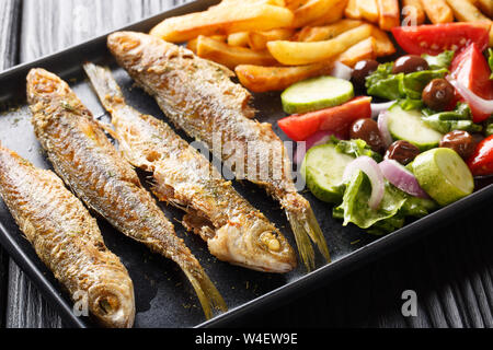 Fried boops boops fish with fresh vegetable salad and french fries close-up on a plate on the table. horizontal Stock Photo
