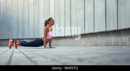 Morning workout. Full-length of young disabled woman with leg prosthesis in sportswear doing stretching exercises outdoors. Disabled sport concept. Motivation. Healthy lifestyle Stock Photo