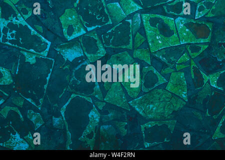 Cracked old tile at the bottom of the pool. Abstract background of battered dark blue and green mosaic. Broken, shabby tiles pattern, texture. Stock Photo