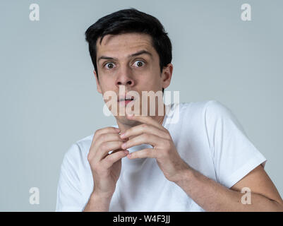 Young man feeling scared and shocked making fear, anxiety gestures. Looking terrified and desperate trying to cover himself. Portrait with copy space. Stock Photo