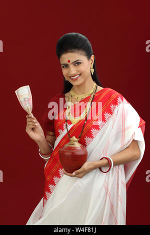 Bengali woman holding Indian banknote and a piggy bank Stock Photo - Alamy