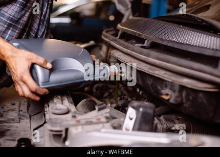 Car mechanic changing engine oil Stock Photo