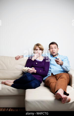 Scared young couple watching tv Stock Photo