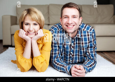 Happy young couple lying on the carpet at home Stock Photo
