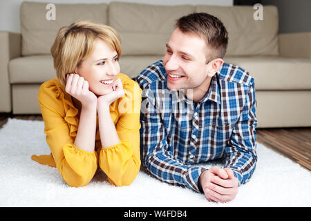 Portrait of cute couple lying on floor in new apartment and looking at each other Stock Photo