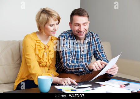 Happy couple calculating bills sitting sonf sofa in living room Stock Photo