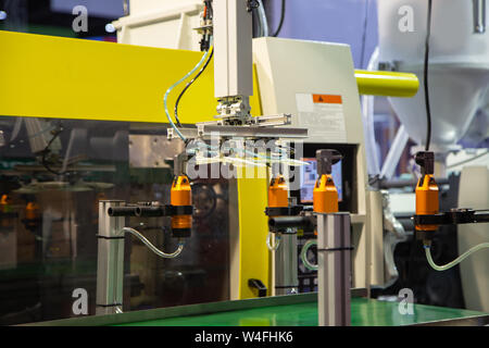 Robotic arm unloading plastic workpiece from plastic injection molding machine Stock Photo