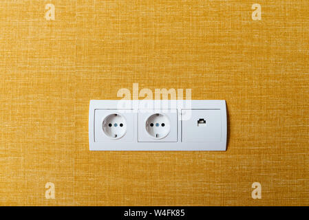 White double socket and ethernet plug on yellow wall Stock Photo