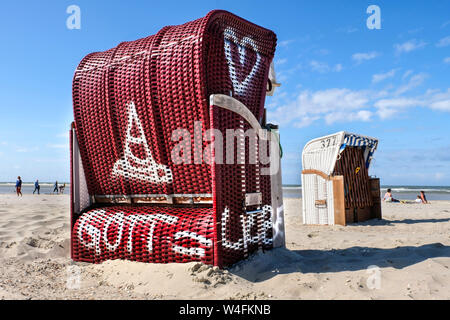 Beach chair with the inscription 'GOD = LOVE'. Ecumenical church beach chair of the Evangelical and Catholic Church stands in the summer season 2019 on the beach of the East Frisian island Spiekeroog, Germany   ---   Strandkorb mit der Aufschrift 'GOTT = LIEBE'. Ökumenischer Kirchen-Strandkorb der evangelischen und katholischen Kirche steht in der Sommersaison 2019 am Strand der ostfriesischen Insel Spiekeroog, Deutschland Stock Photo