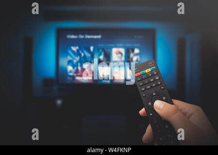 VOD service screen. Man watching TV with remote control in hand. Stock Photo