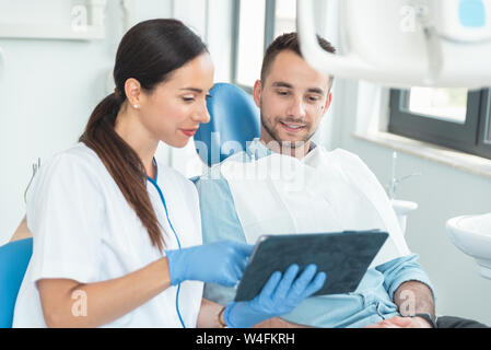 Female dentist with digital tablet. Modern treatment in professional dental clinic. Stock Photo