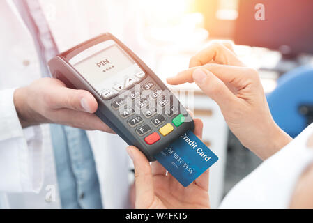 Payment by credit card with terminal. Woman enters the pin code Stock Photo