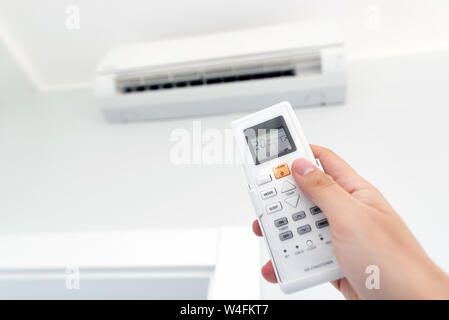 Adjusting temperature of air conditioner by remote. Air conditioning system Stock Photo