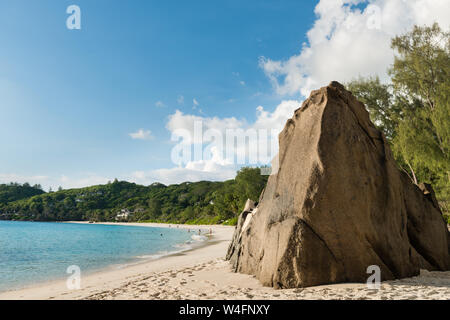 Big stone on sandy Seychelles beach landscape. Palm trees, ocean, tropical plants on background. Stock Photo