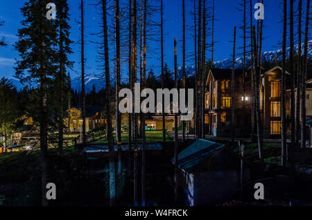 Nocturnal view of snow capped Pir Panjal Range looking over houses and hotels amidst pine trees at Gulmarg, Jammu and Kashmir, India Stock Photo