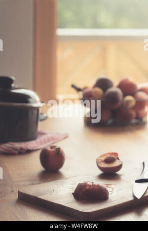 Making peaches jam on wooden table in natural light. Kitchen table in front of balcony glass door Stock Photo