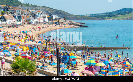 Lyme Regis, Dorset, UK. 23rd July 2019. UK Weather: Crowds of holidaymakers flock to the picturesque seaside resort of Lyme Regis to soak up the scorching hot sunshine and on the first week of the school summer holidays.  Holidaymakers and families swelter in the hot sunshine on the town's packed beach while others take a cooling dip in the sea on what is set to be the hottest week of the year so far as the African Plume hits southern Britain. Credit: Celia McMahon/Alamy Live News. Stock Photo
