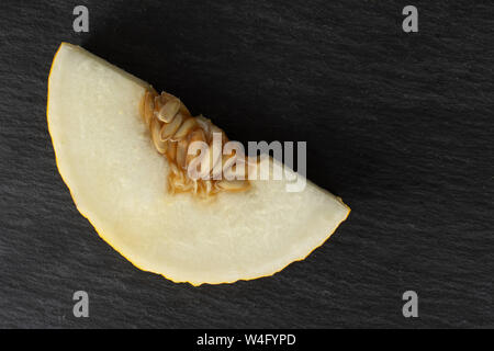 One slice of fresh yellow melon canary flatlay on grey stone Stock Photo
