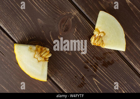 Group of two pieces of fresh yellow melon canary flatlay on brown wood Stock Photo