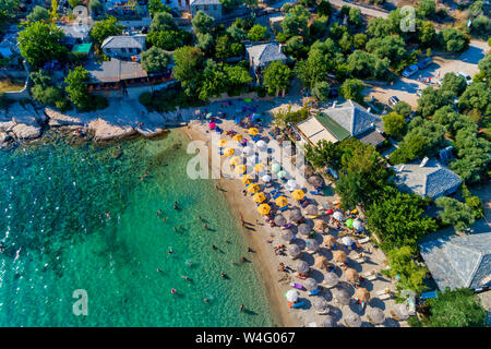 Aerial View of the Aliki Beach with colorful umbrellas, at Thassos island, Greece. swimming people in sea Stock Photo
