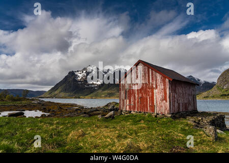 Old weathered Red hut or Rorbuer on the shores of a fjord, Lofoten Islands, Norway on a bright sunny spring day Stock Photo