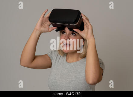 Curious woman happy and excited to use virtual reality goggles feeling excited about simulation, exploring virtual life making happy gestures. In New Stock Photo
