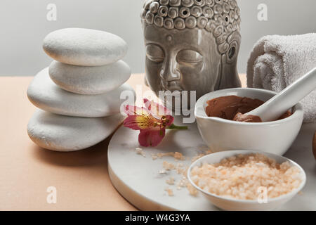 clay and sea salt in bowl near Buddha figurine and spa stones on marble circle isolated on grey Stock Photo