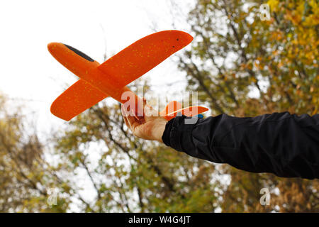 Closeup view of hand of happy caucasian child boy playing with toy airplane outside. Dream, imagination, curiosity concept. Horizontal color photograp
