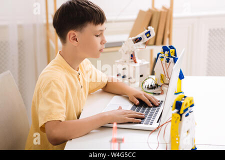 Boy creating robotics project on laptop in class Stock Photo