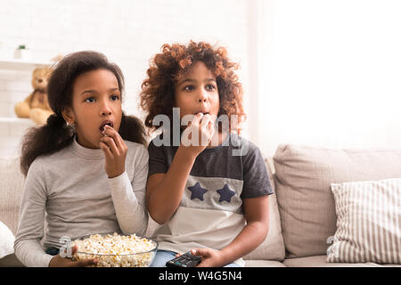 Interested girls watching discovery film and eating popcorn Stock Photo