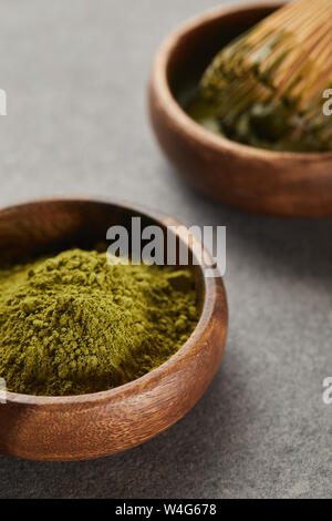 selective focus of green matcha powder and bamboo whisk in wooden bowl Stock Photo