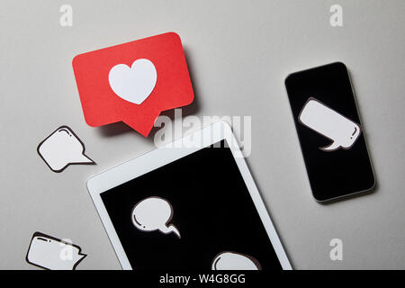 paper like sign over digital tablet and smartphone with thought and speech bubbles on white surface Stock Photo