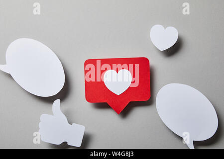 red like card, speech bubbles, thumbs up and small paper heart on white surface Stock Photo