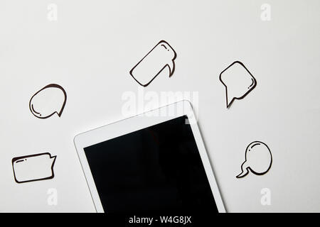 digital tablet with paper thought and speech bubbles on white surface Stock Photo