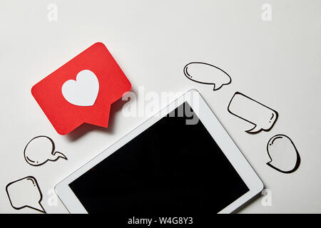 digital tablet with like sign card, paper thought and speech bubbles on white surface Stock Photo