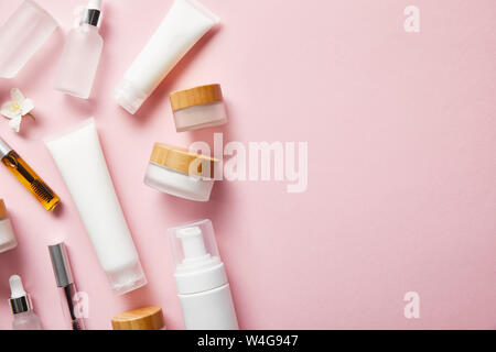 top view of different cosmetic containers and jasmine flower on pink Stock Photo