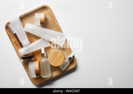 plenty of empty cosmetic containers on wooden tray on white Stock Photo