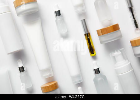 flat lay of cream tubes with hand cream, mascara bottles, cosmetic glass bottles, cosmetic dispensers and jars on white Stock Photo