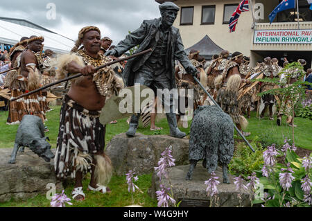 Zulu warriors beside the drover's statue at the Royal Welsh showground in Llanelwedd. Visit of King Goodwill of the Zulu Nation to the Royal Welsh Show (RWAS) at Builth Wells. Llanelwedd, Powys, Wales. Stock Photo