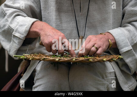 Close up of craftsman wearing rural clothes making wicker basket of twigs. Traditional handmade weaving technique at rural village Stock Photo