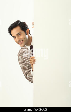 Businessman hiding behind a placard and smiling Stock Photo
