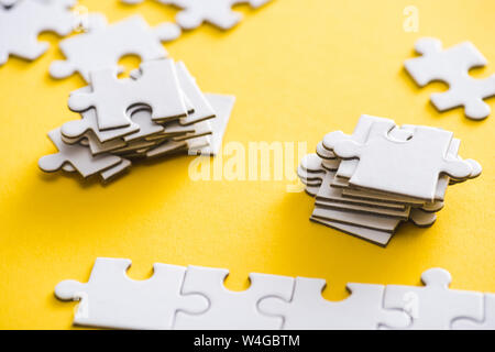 selective focus of connected and unfinished puzzle pieces on yellow Stock Photo