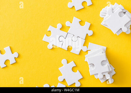 top view of white stack of jigsaw near connected puzzles isolated on yellow Stock Photo