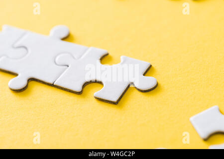 selective focus of connected white puzzle pieces on yellow Stock Photo